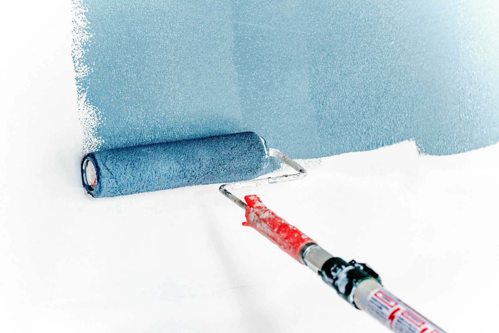 Wand wird mit Farbroller in Blau gestrichen